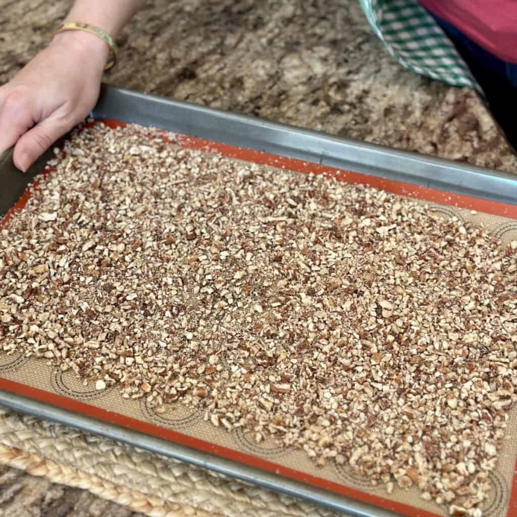 Spreading pecans on a sheet pan.