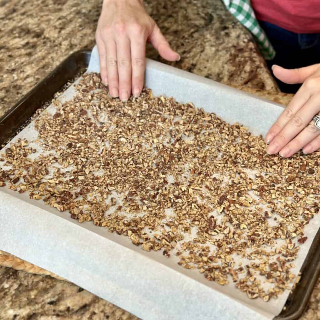 Spreading pecans on a sheet pan.