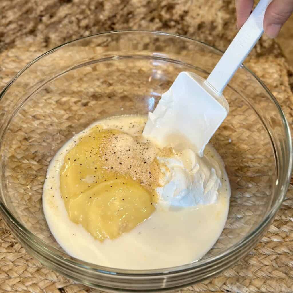 Mixing together the ingredients for chicken cordon bleu casserole in a bowl.