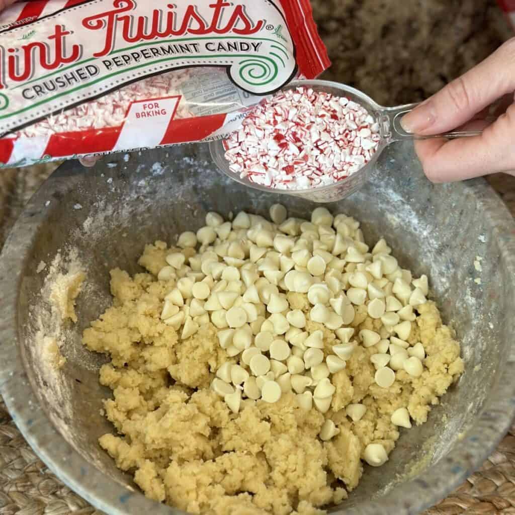 Adding peppermint and white chocolate chips to cookie dough.