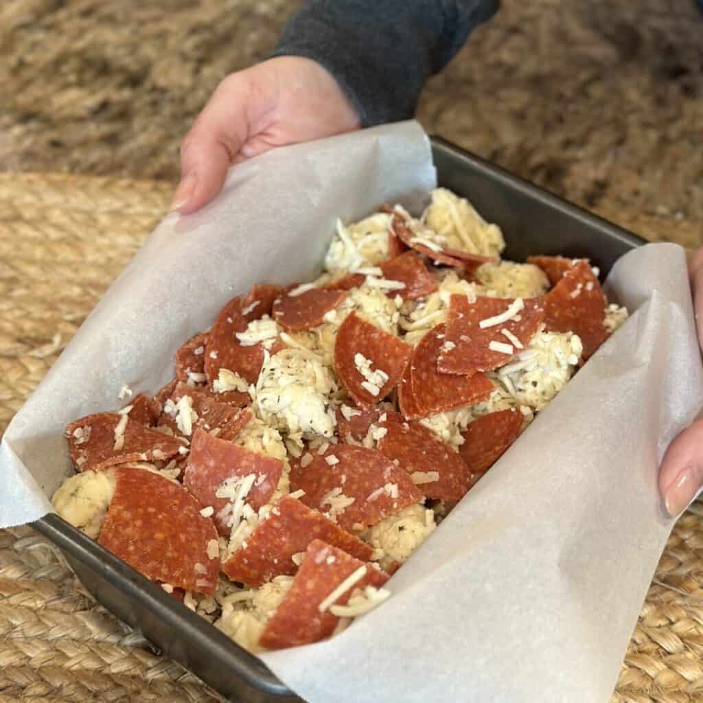 The raw dough for pizza monkey bread in a pan.