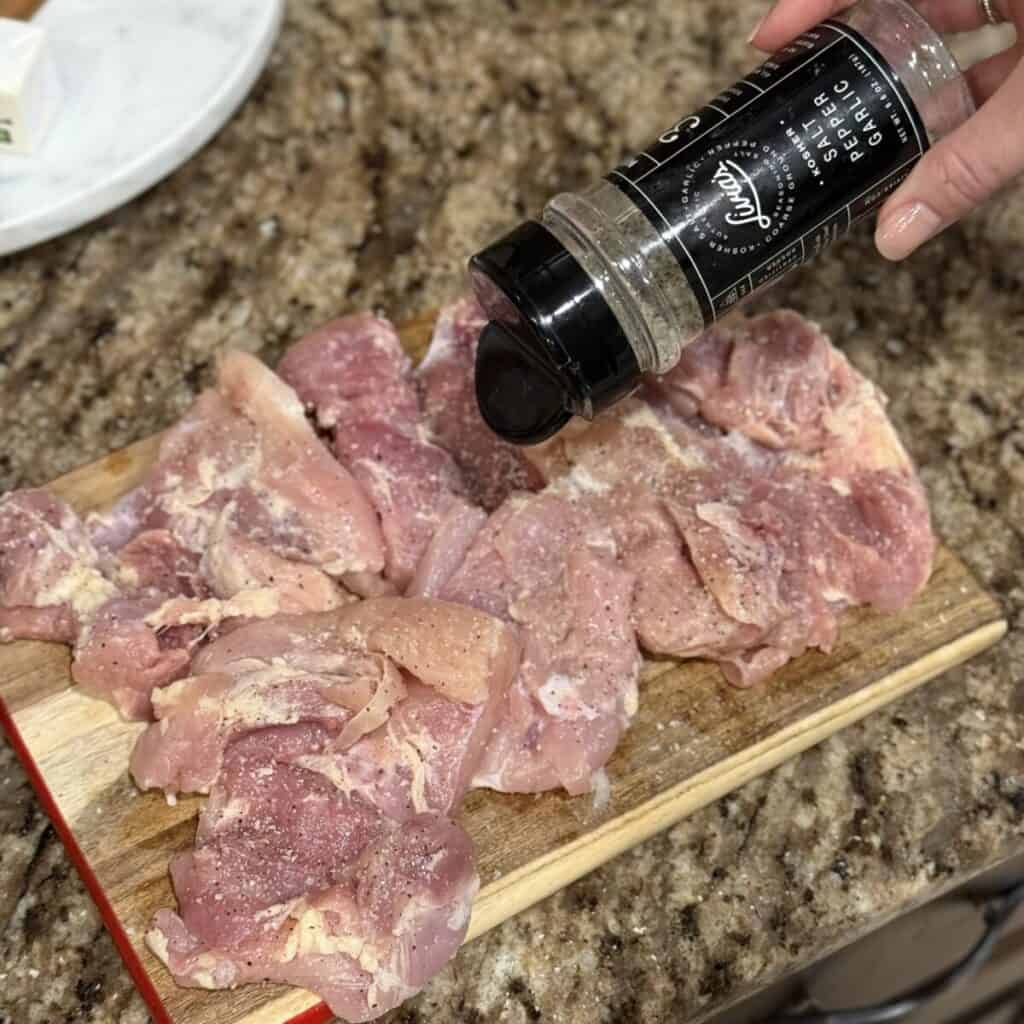 Seasoning chicken on a cutting board.