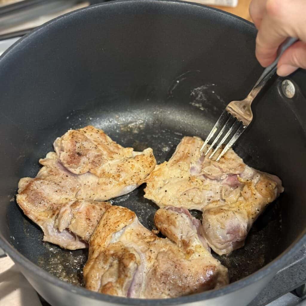 Searing chicken in a skillet.