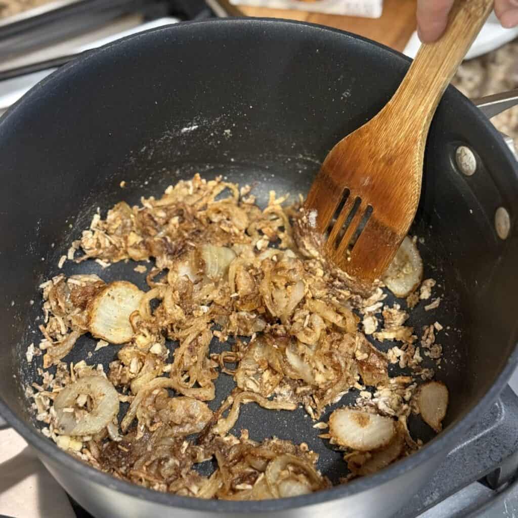 Stirring flour and onions in a pan.