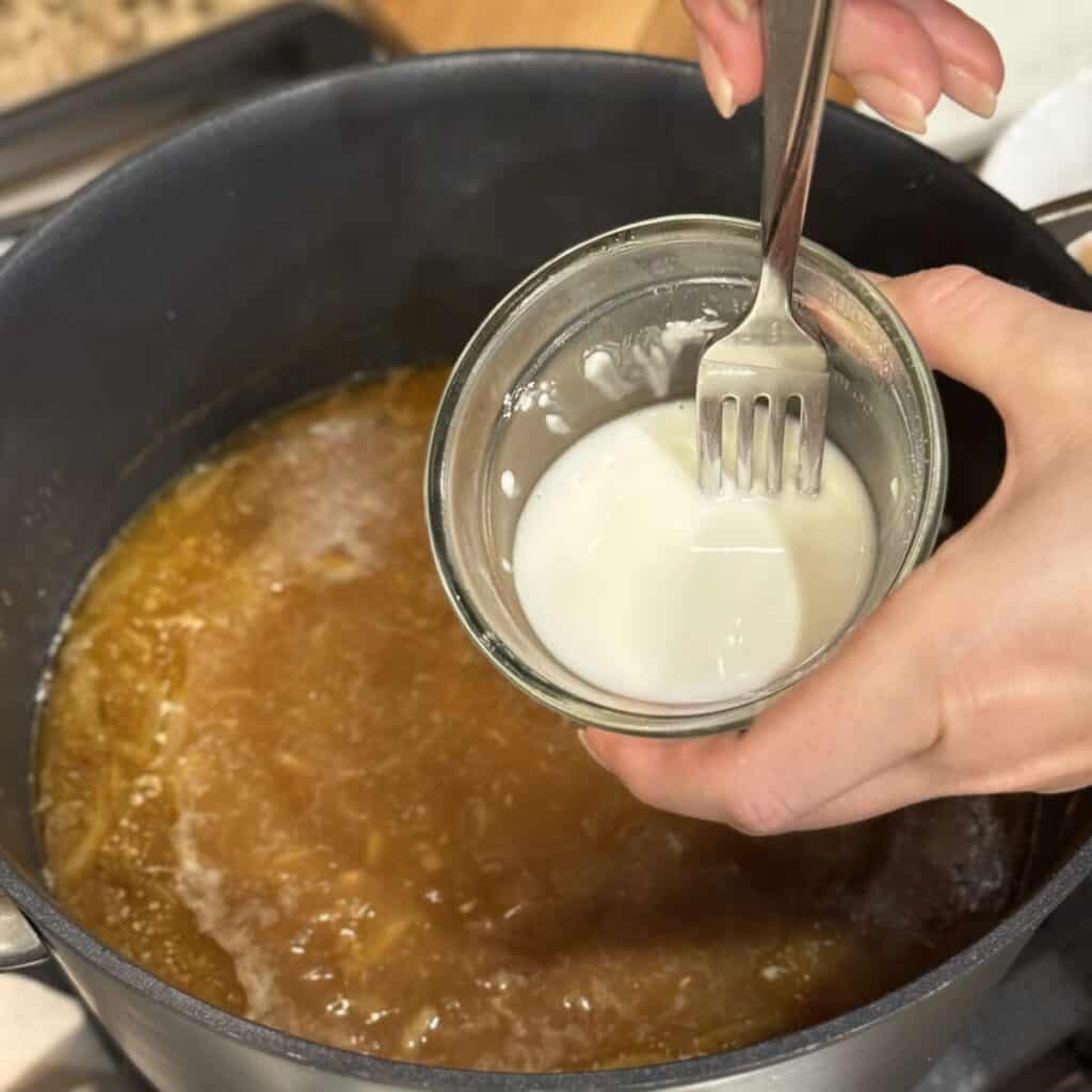 Whisking a cornstarch slurry in a bowl.