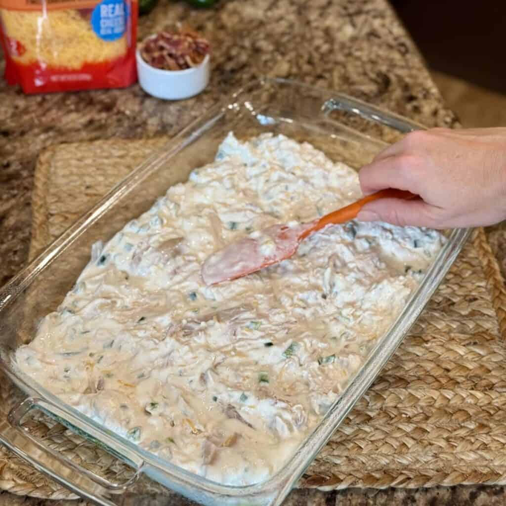 Spreading a base for a cream cheese casserole in a baking dish.