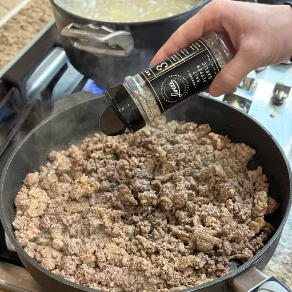 Seasoning ground beef in a skillet.