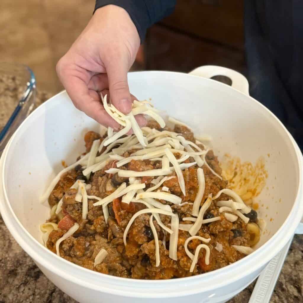 Adding cheese to pizza pasta.