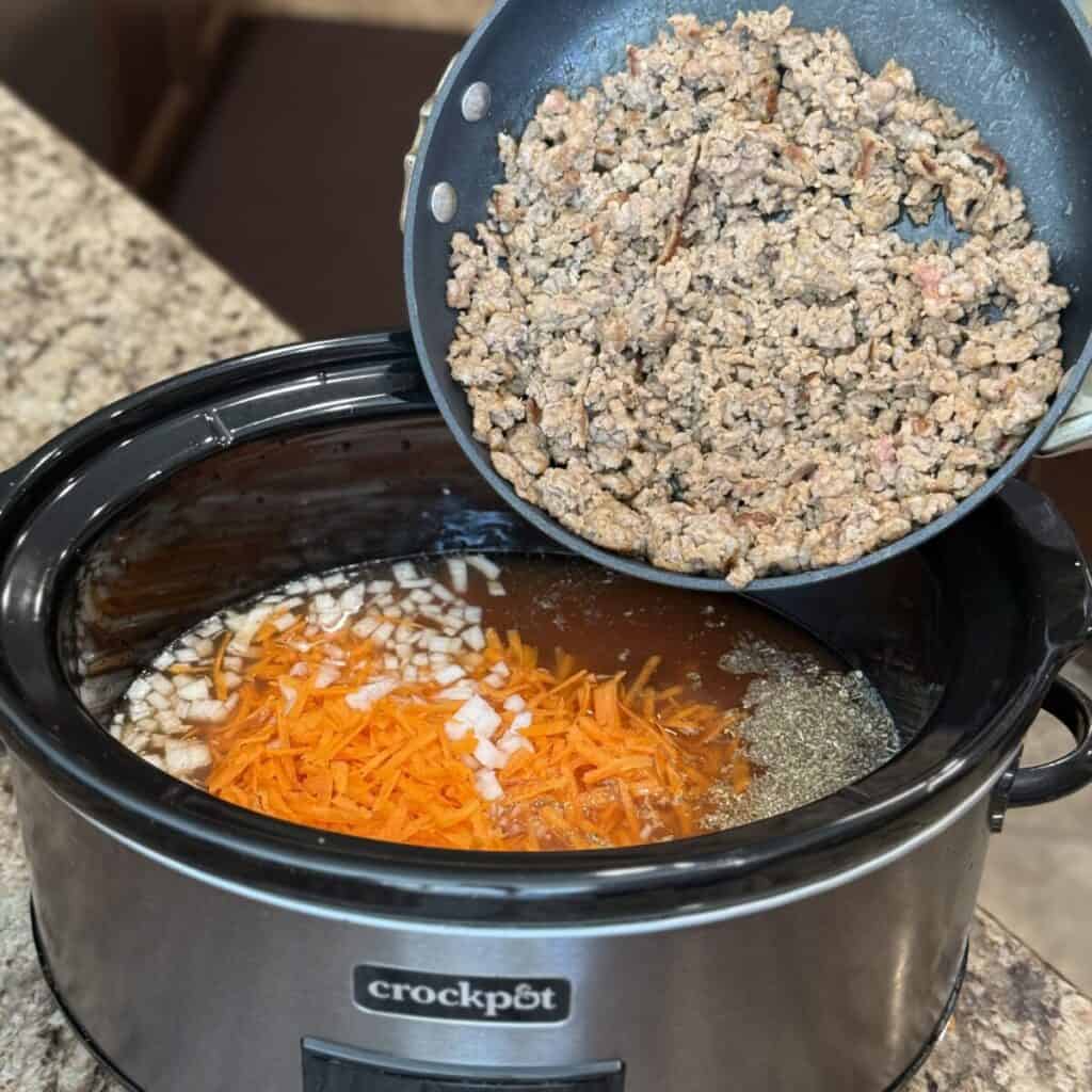 Stirring crockpot sausage tortellini soup in a crockpot.