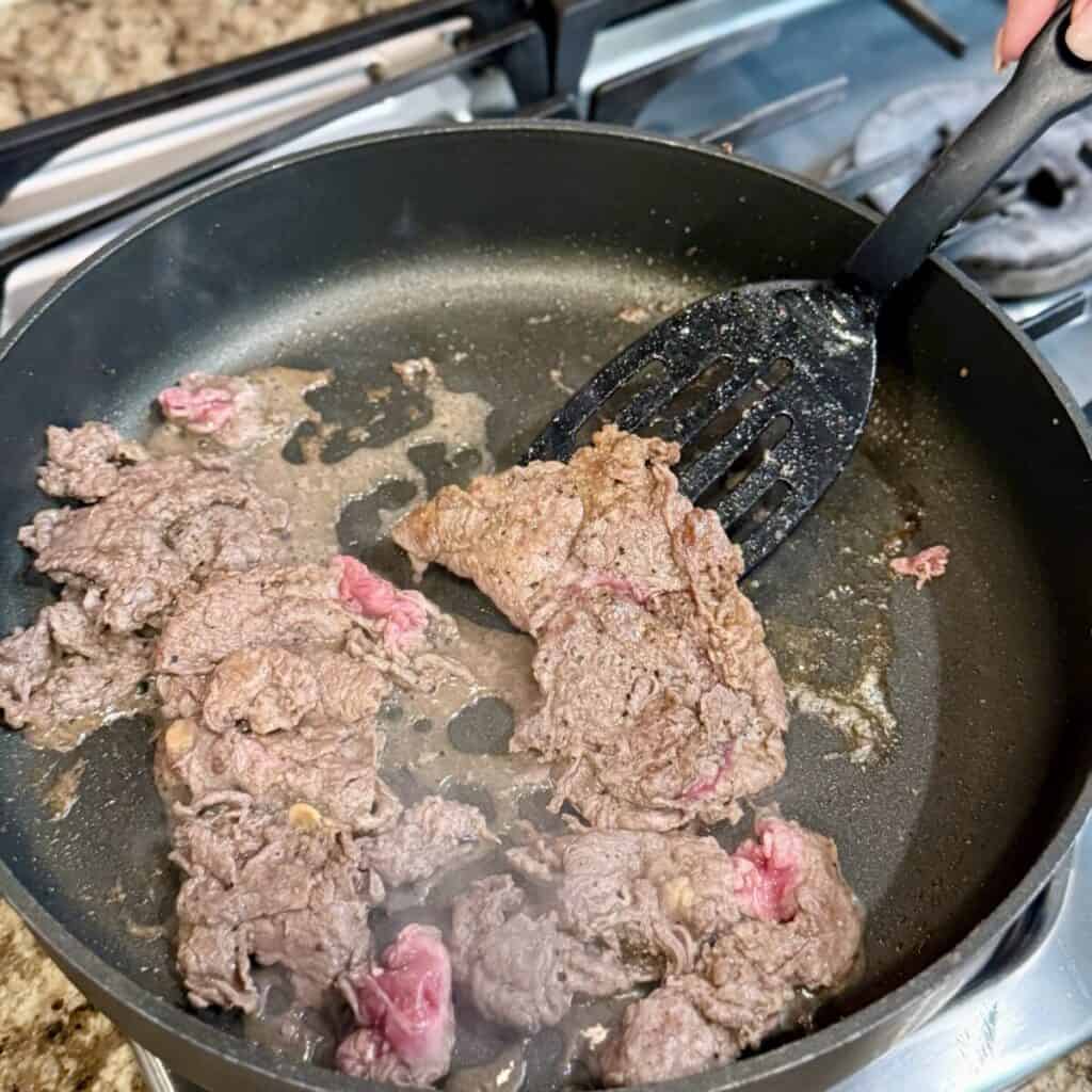 Searing steak in a pan.