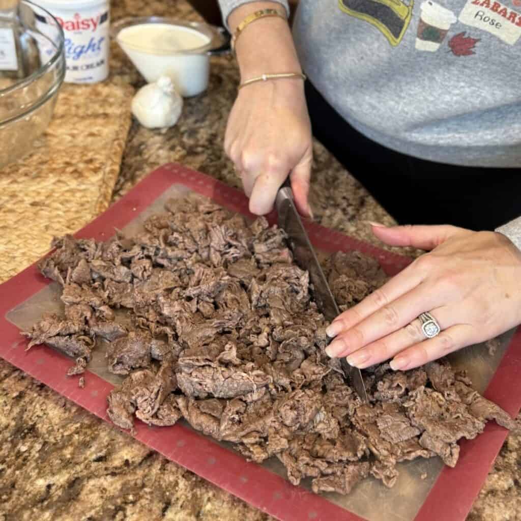 Chopping steak on a cutting board.