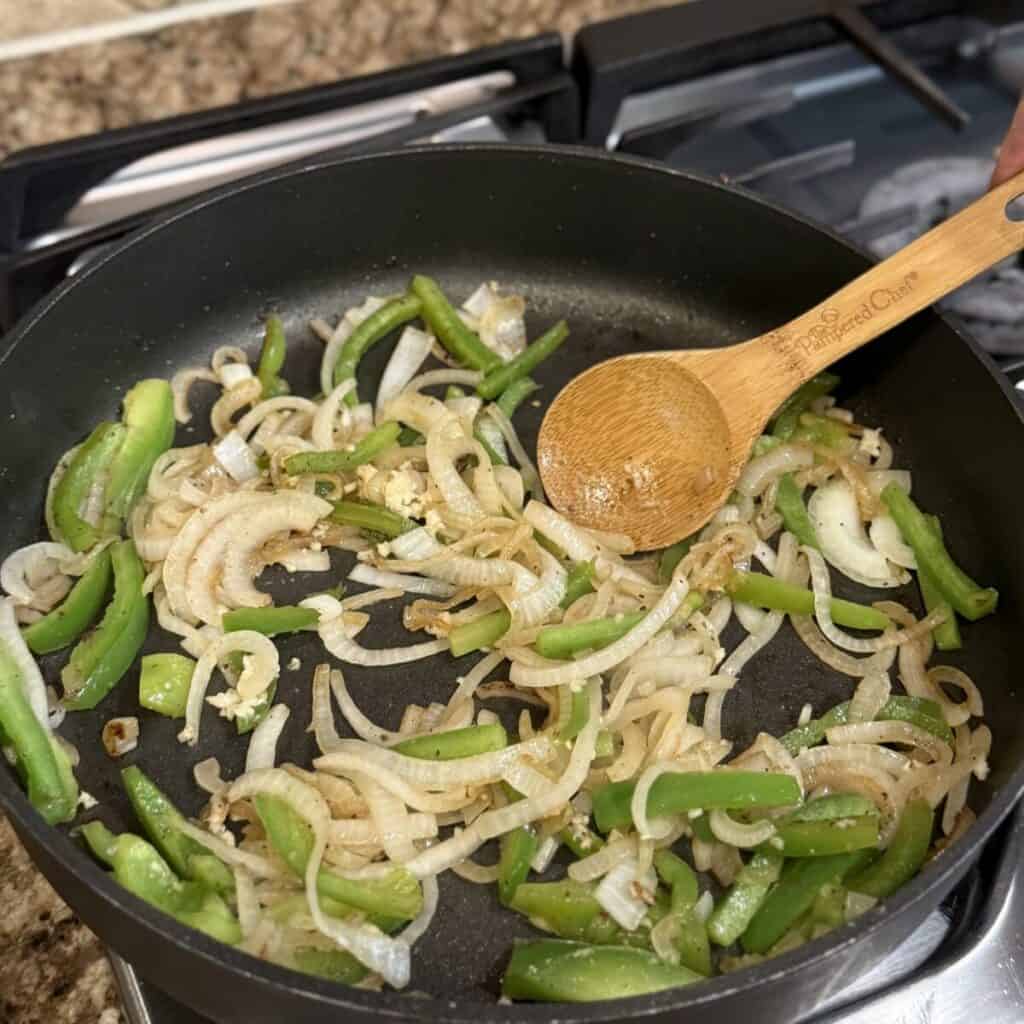 Sautéing onion and green peppers in a skillet.