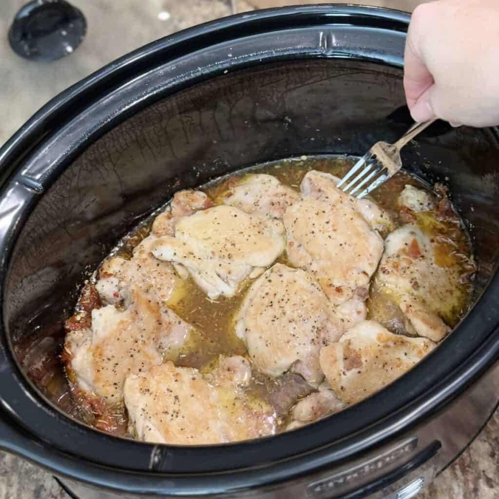 Adding chicken to a crockpot.