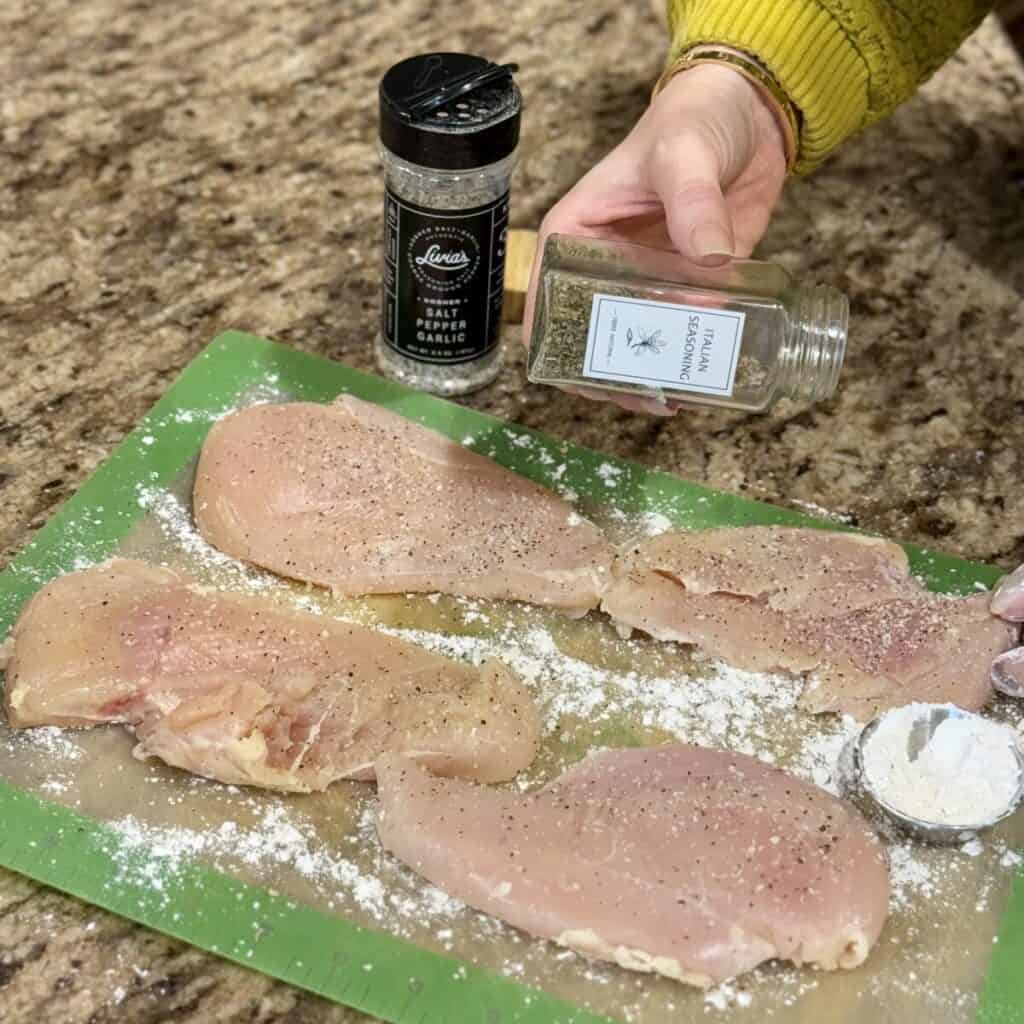 Seasoning chicken breasts.