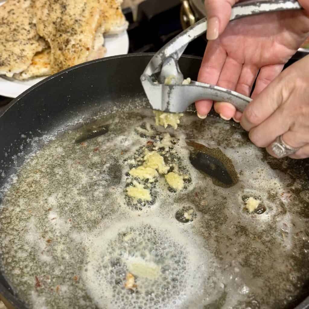 Adding garlic to butter in a skillet.