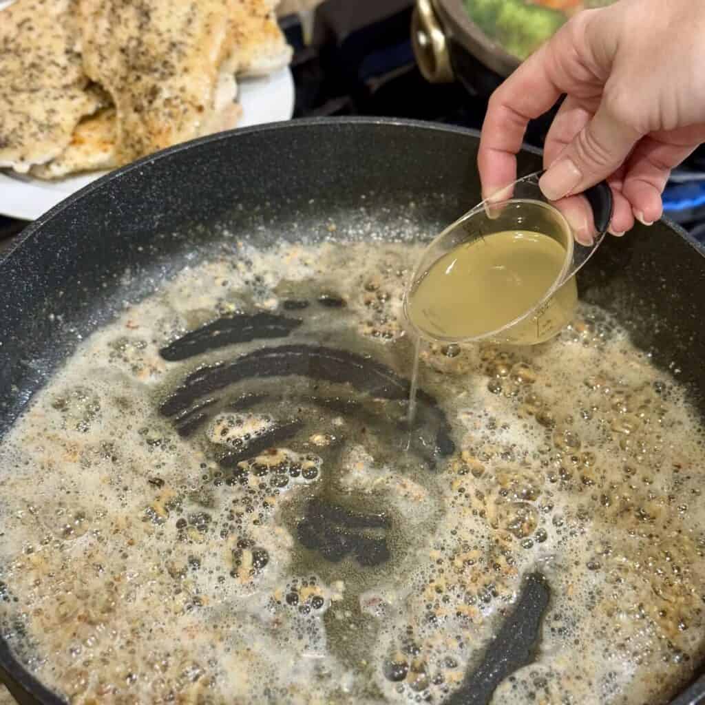 Adding broth to butter in a skillet.