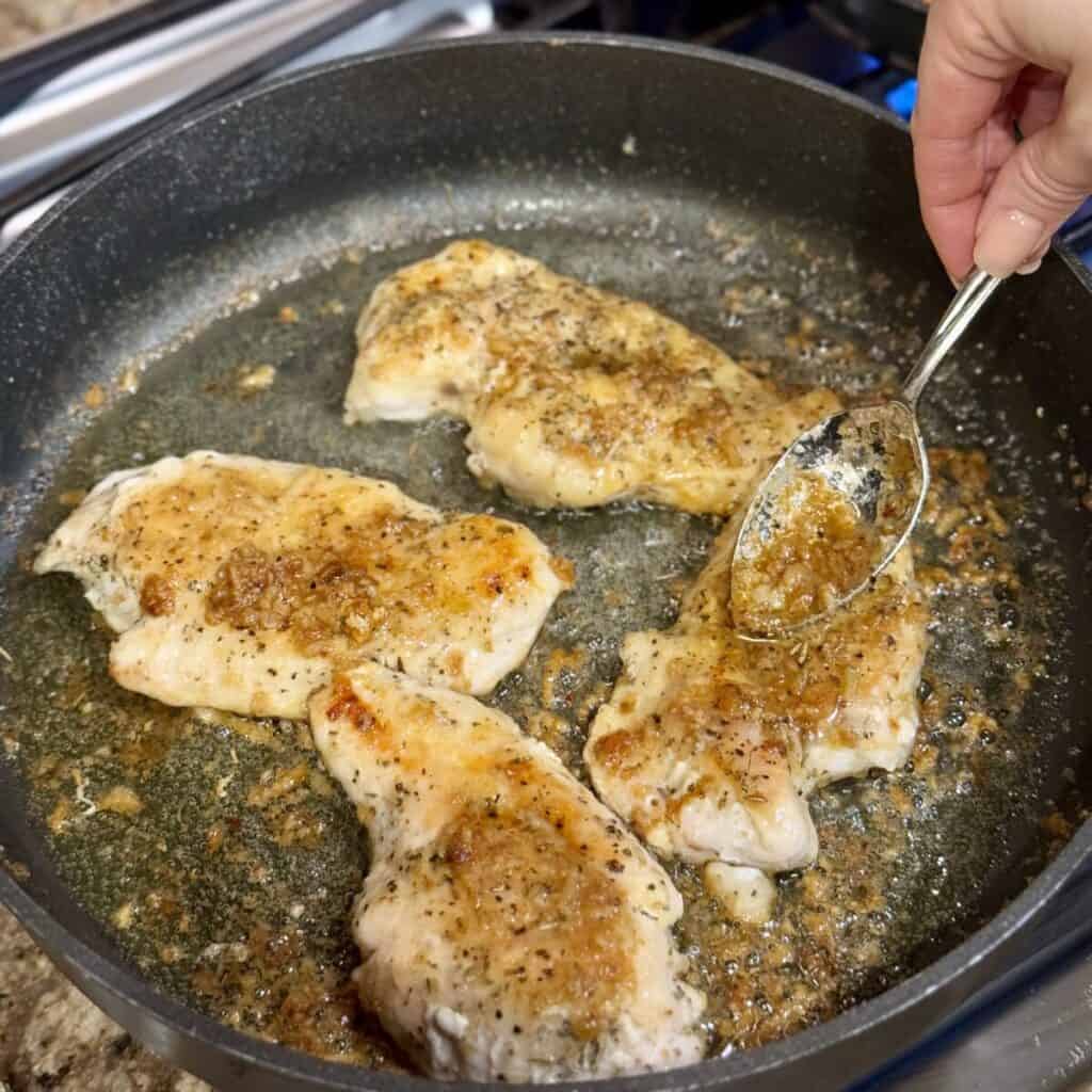 Cooking chicken in garlic butter in a skillet.