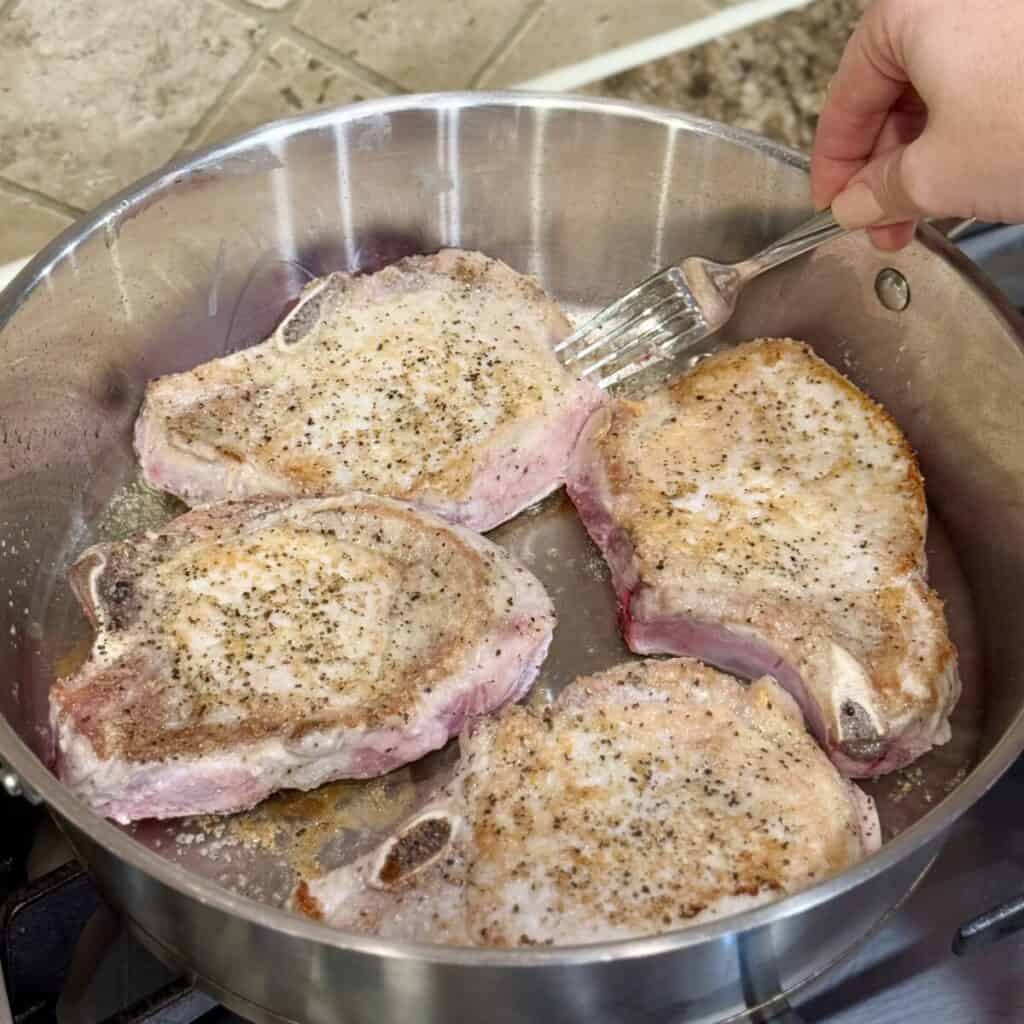 Searing pork chops in a skillet.