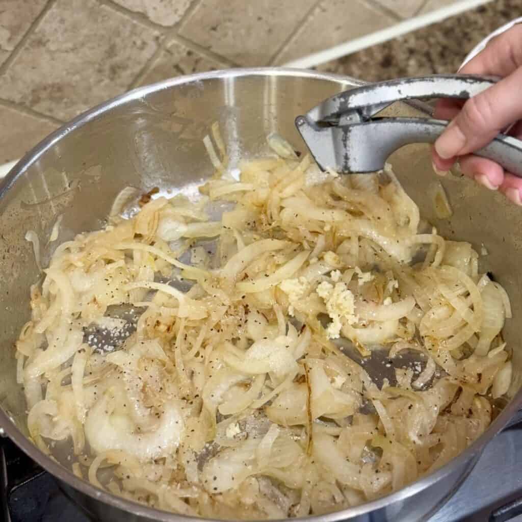 Adding garlic to onions in a pan.