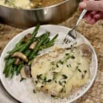 French onion pork chop on a plate with rice and green beans.