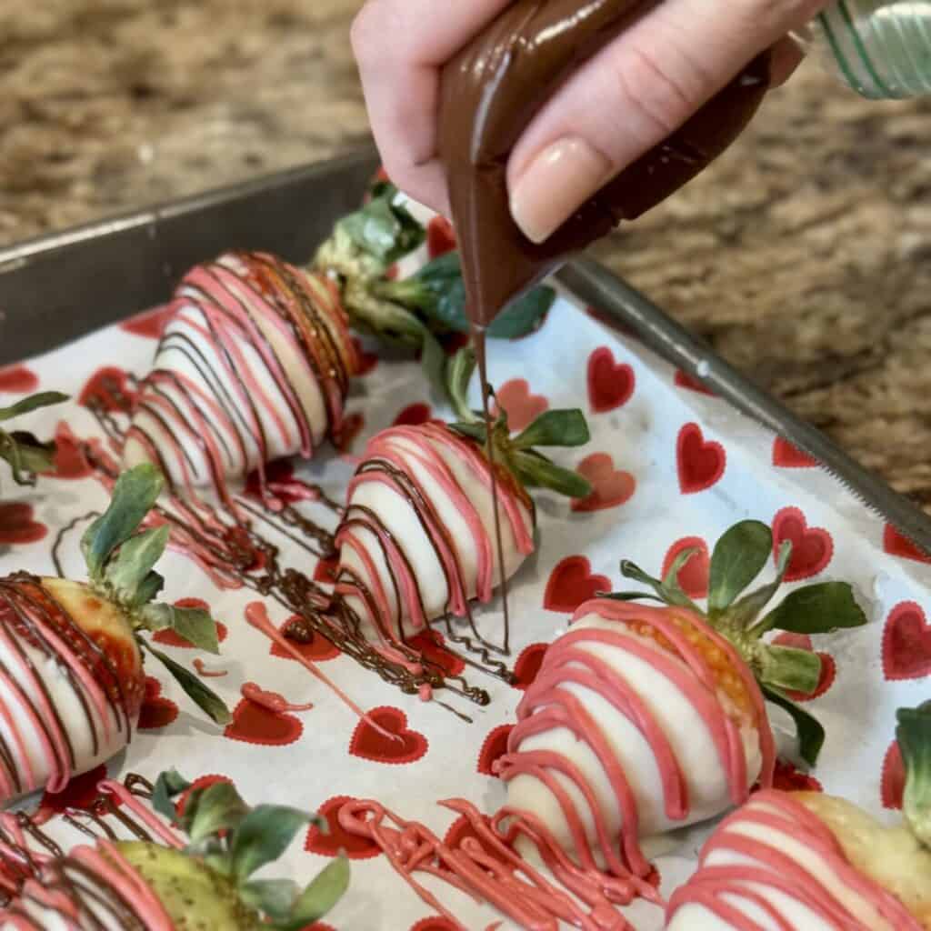 Drizzling dyed chocolate on white chocolate covered strawberries.