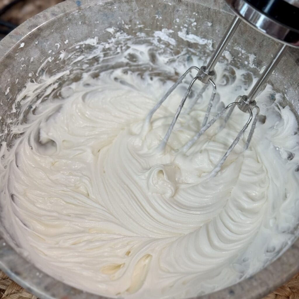 Whipping icing for red velvet cake in a bowl.