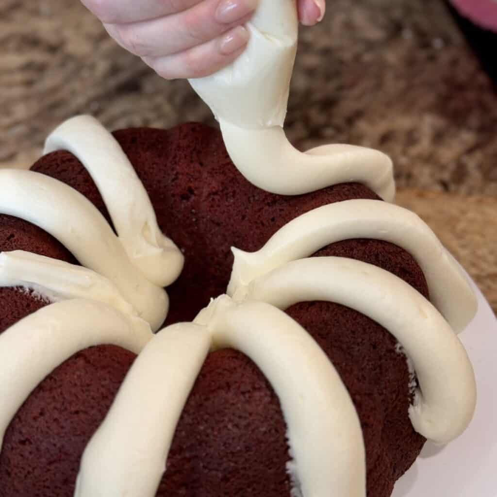 Putting icing on red velvet cake.