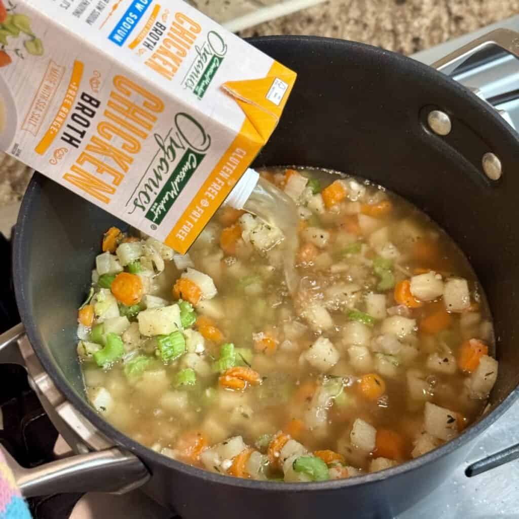 Adding broth to vegetables in a stockpot.