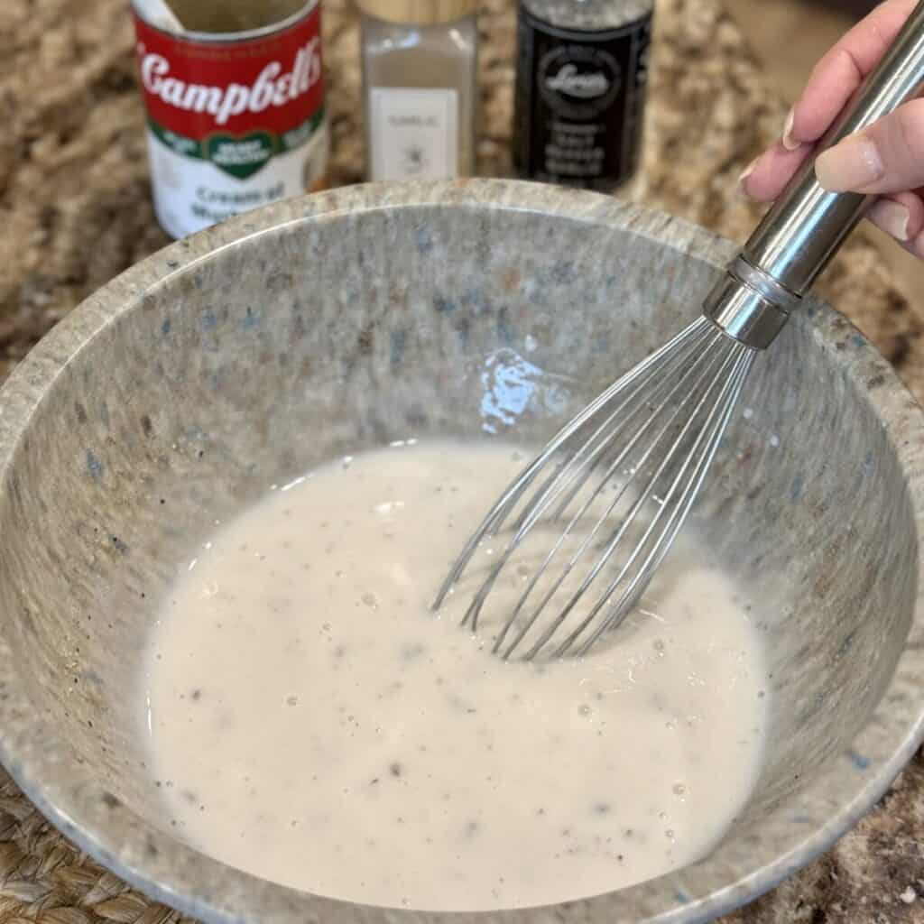 Whisking cream of mushroom soup in a bowl.