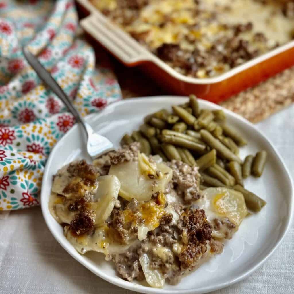 A plate of hamburger potato casserole and green beans.