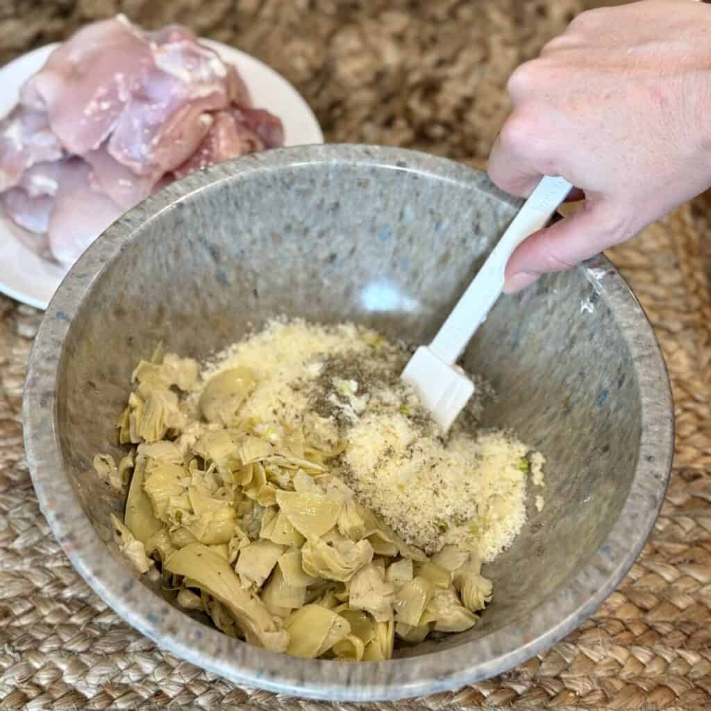 Mixing mayo, artichokes and parmesan in a bowl.