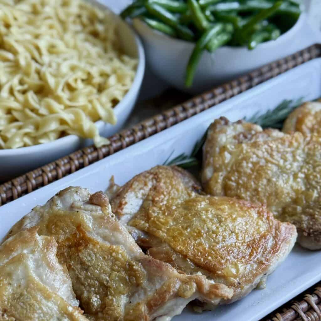 A plate of chicken, noodles and green beans.