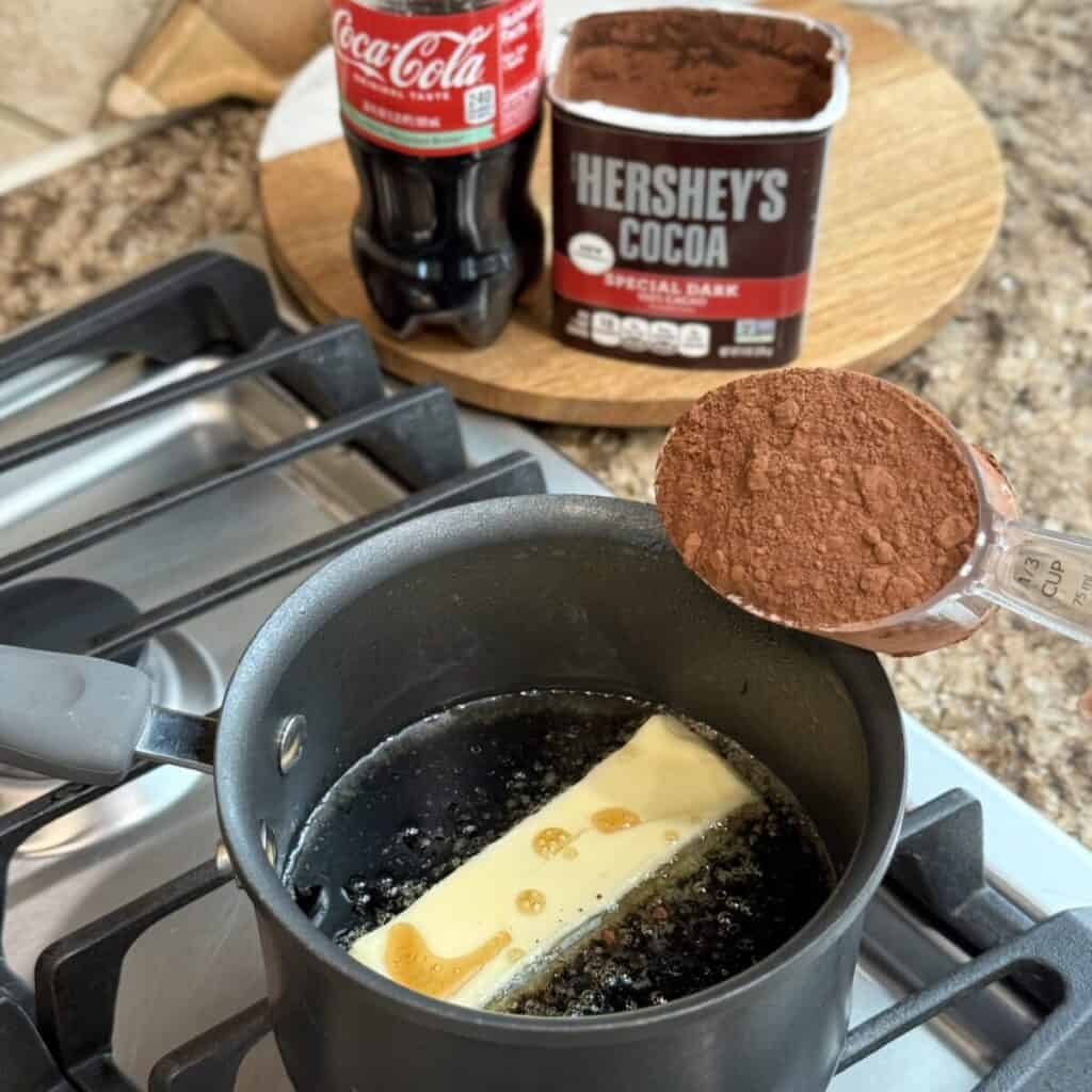 Adding cocoa powder to a saucepan with butter.