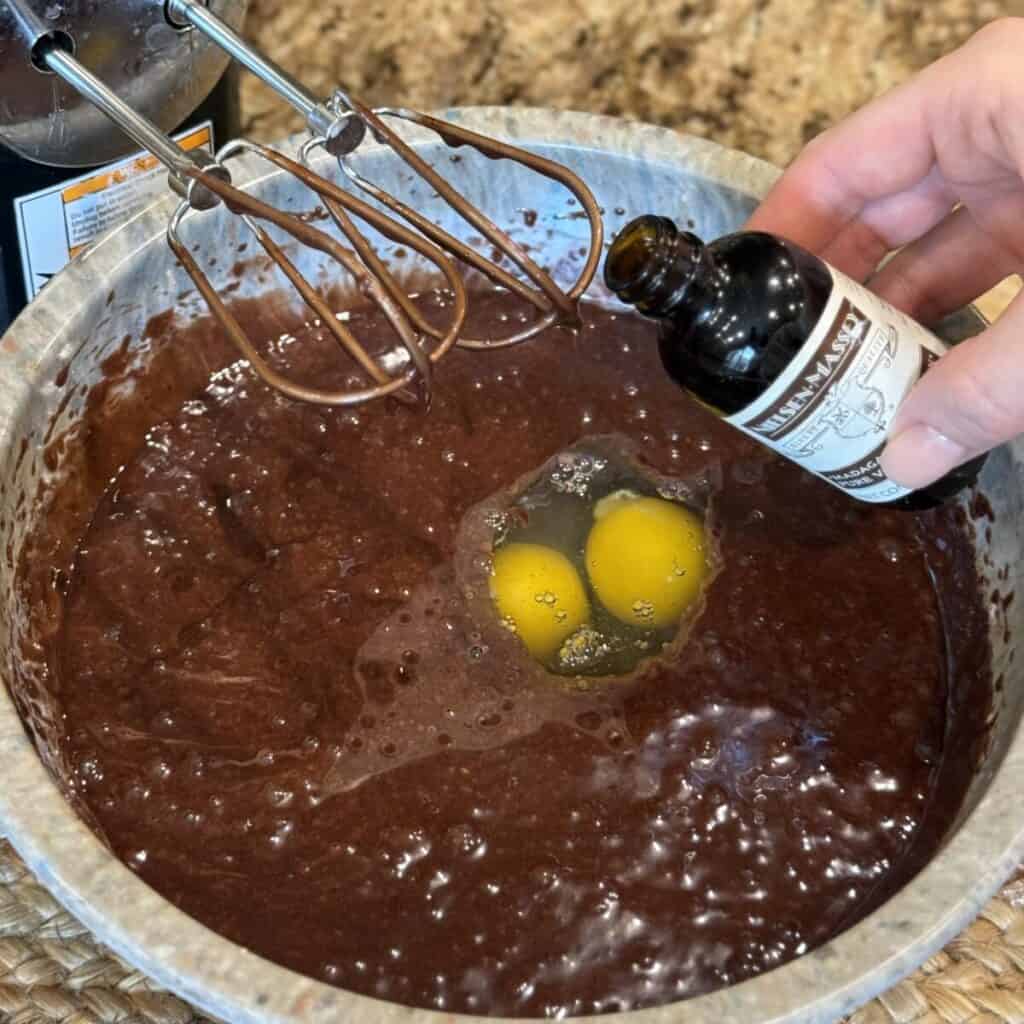 Adding eggs and vanilla to cake batter.