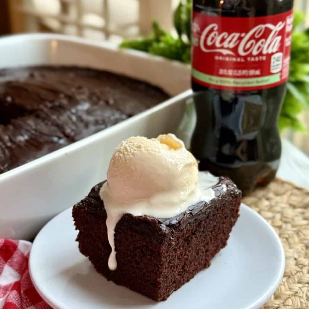 A slice of copycat Cracker Barrel coca-cola cake on a plate with ice cream.