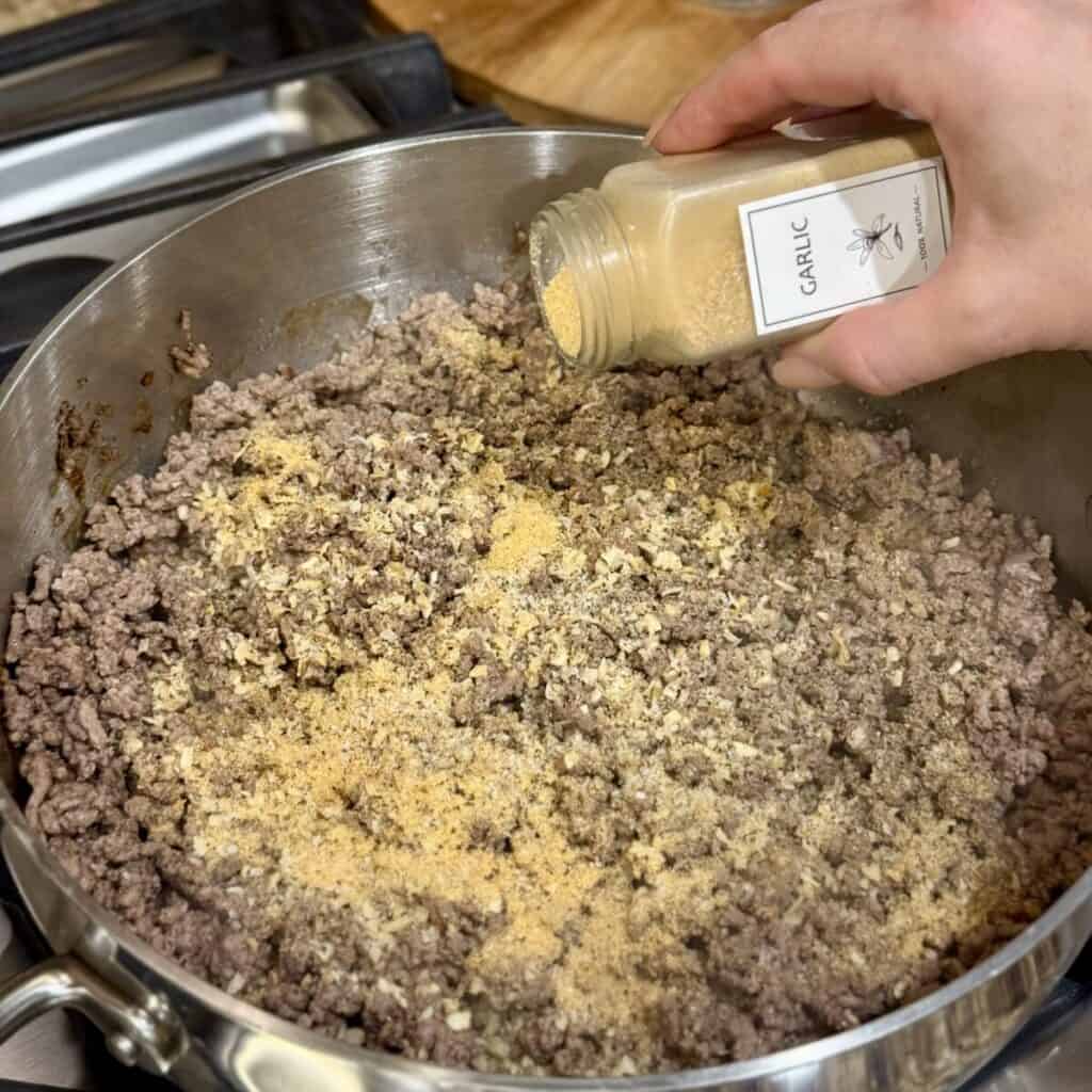 Seasoning ground beef in a skillet.