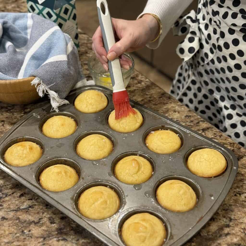 Brushing butter on the tops of rolls.