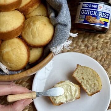 Adding butter to a halved quick yeast roll.